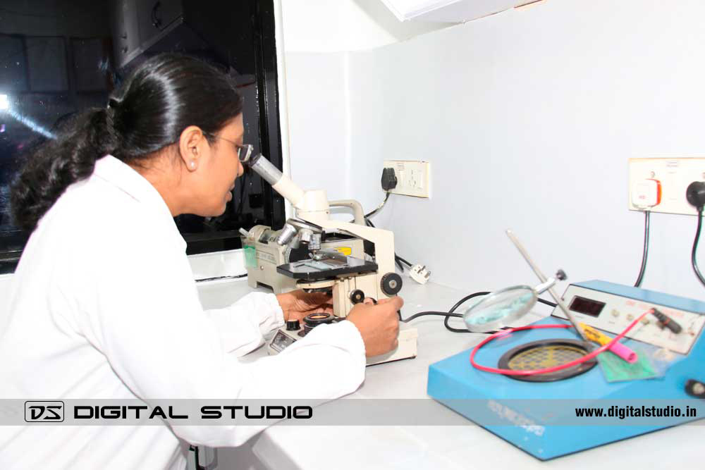 Lady working on microscope in a pharma lab